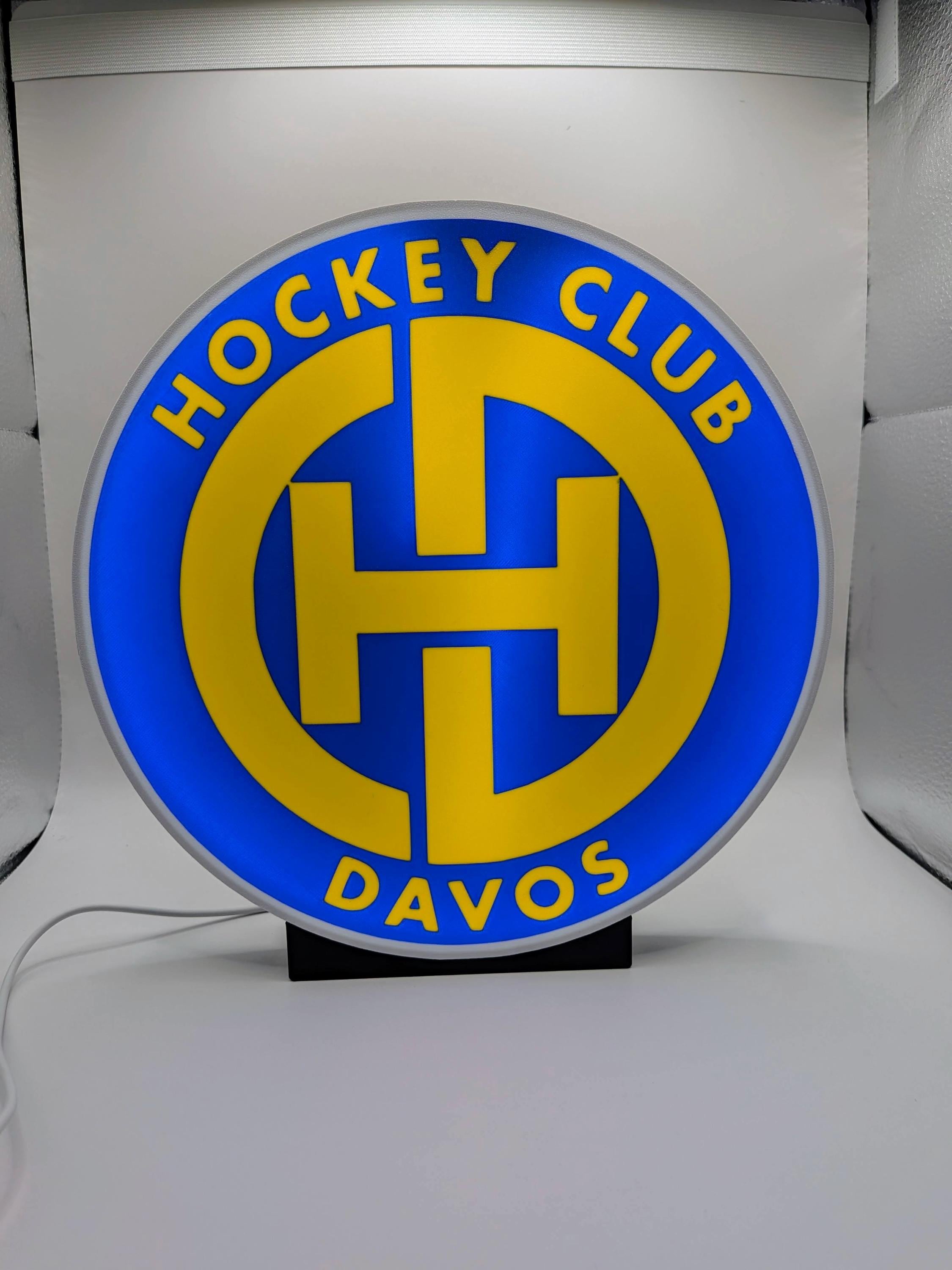 Lampada LED lightbox tonda con logo Hockey Club Davos, base nera, cavo bianco.
