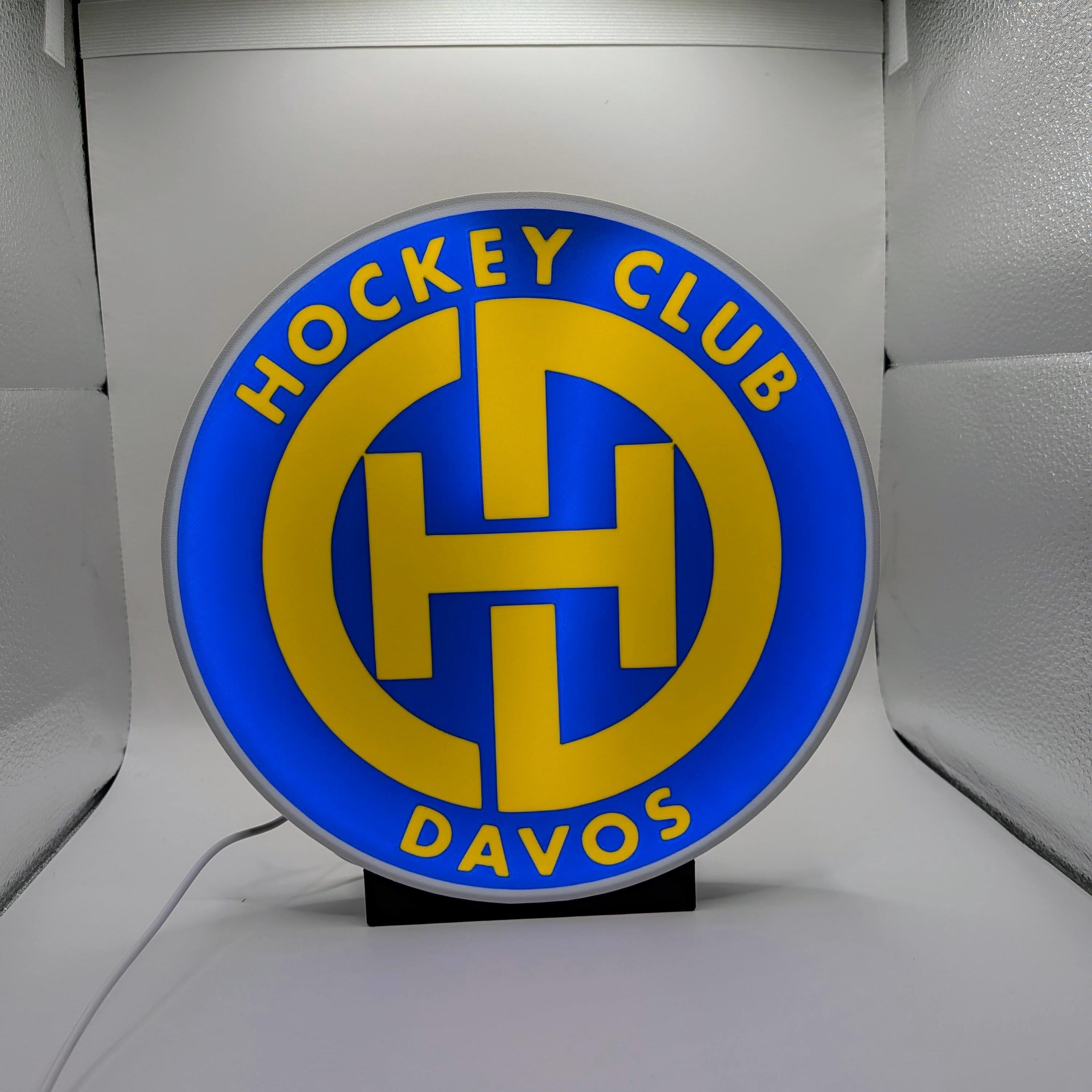 Lampada LED lightbox tonda con logo Hockey Club Davos, cornice grigia, cavo bianco.