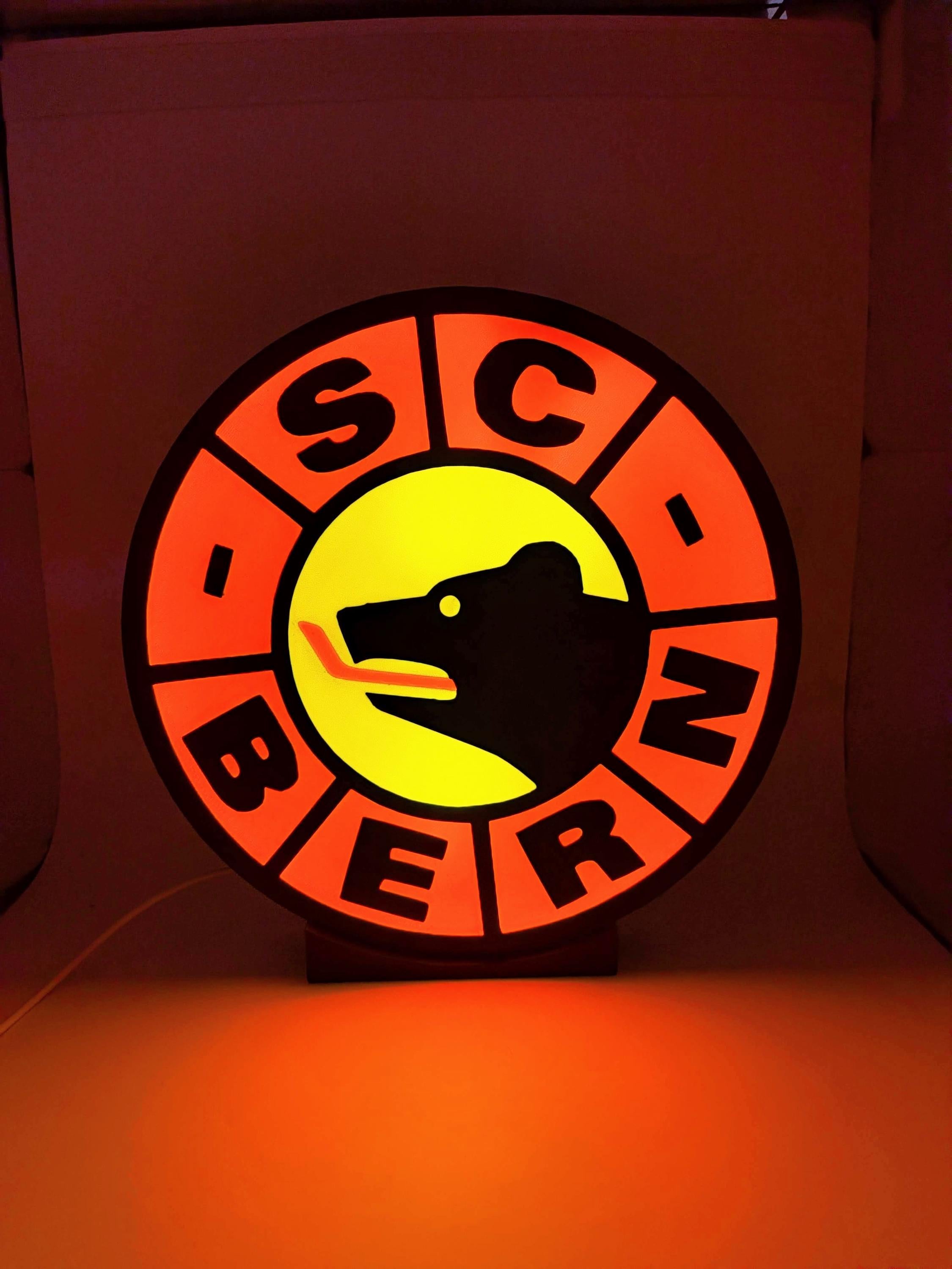 Lampada LED hockey con lightbox circolare su base, corona arancione e logo giallo