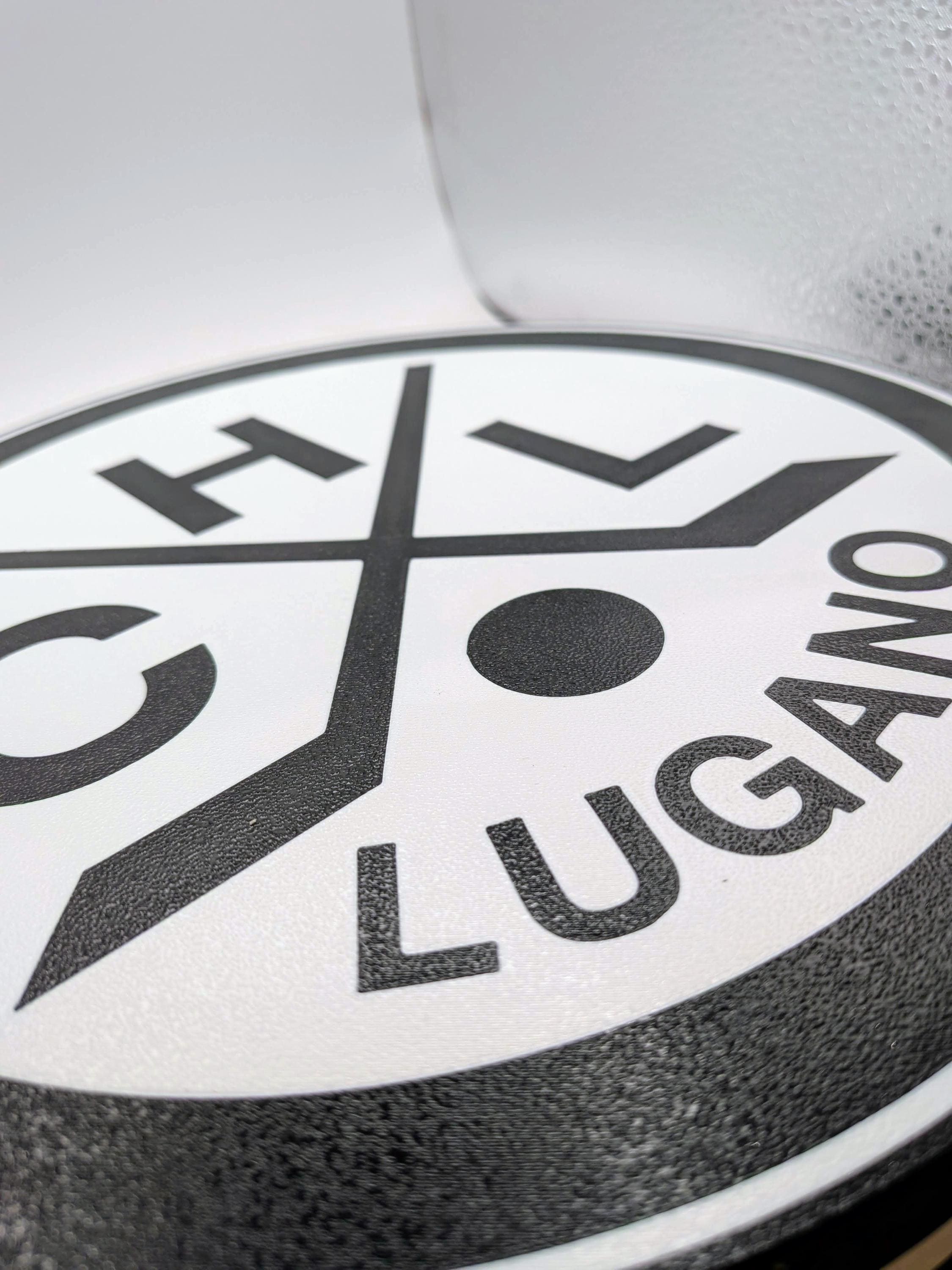 Close-up of Lugano hockey logo print on round LED lightbox panel, black and white