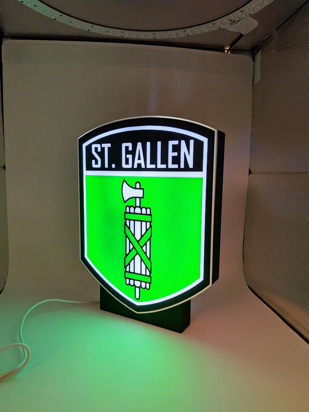 Lampada LED lightbox ST. Gallen con stemma verde luminoso e base nera