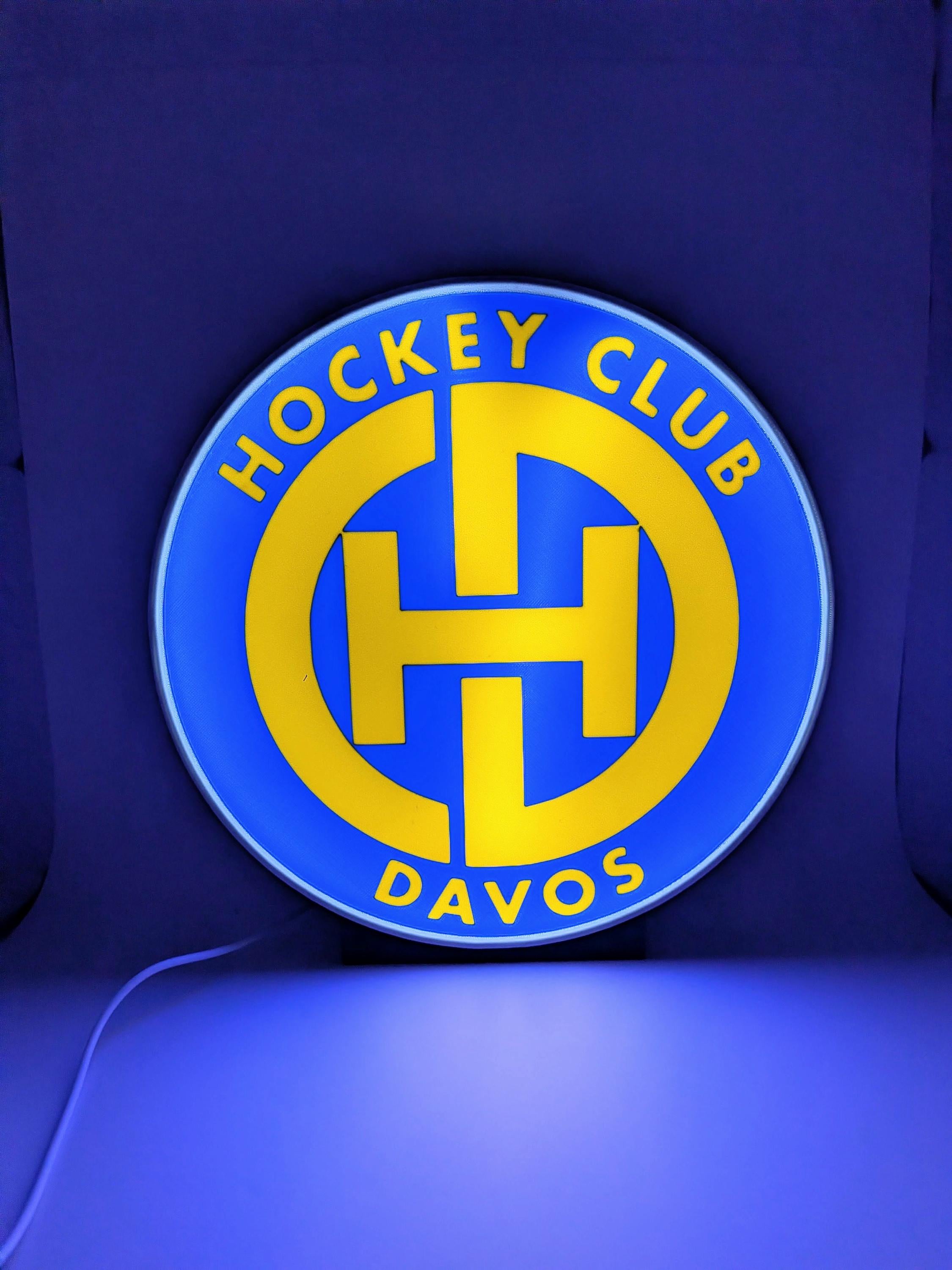 Lampada LED lightbox tonda con logo Hockey Club Davos, bordo grigio, luce blu.