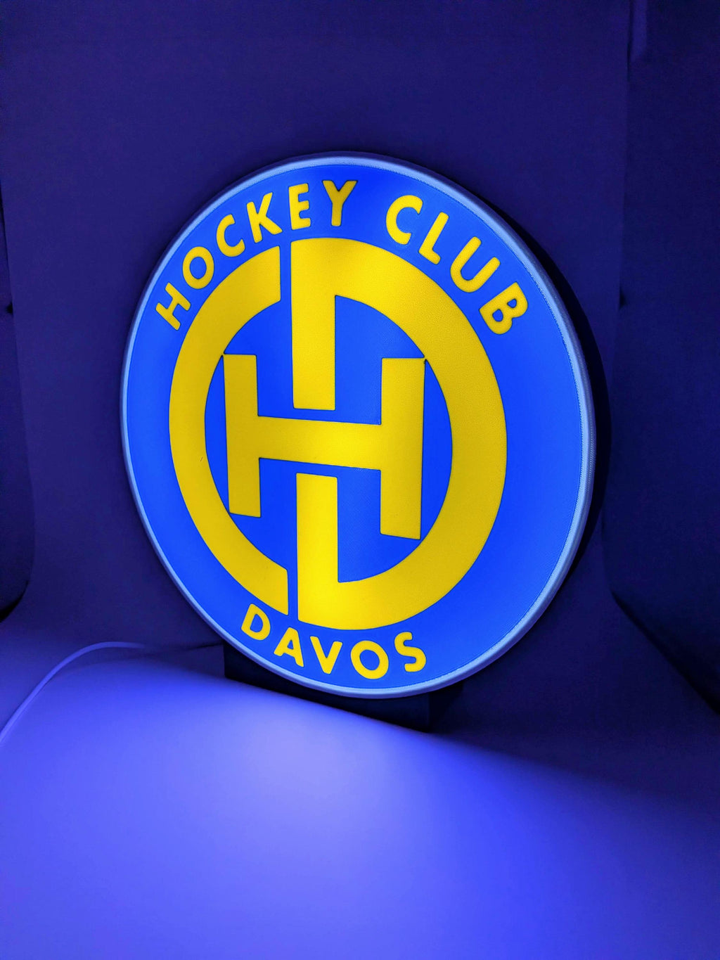 Lampada LED lightbox tonda con logo Hockey Club Davos, bordo grigio, base nera.